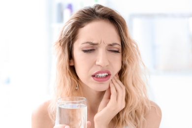 Young woman suffering from toothache indoors