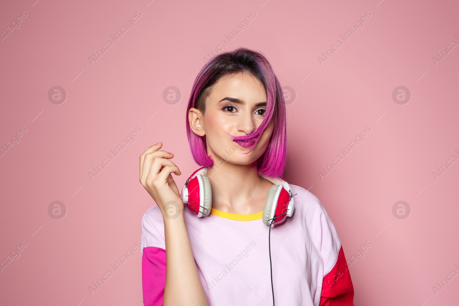 Photo of Young woman with trendy hairstyle and headphones against color background