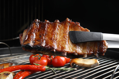 Photo of Delicious ribs and vegetables on barbecue grill