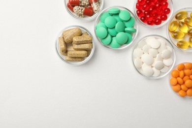 Photo of Different dietary supplements in bowls on white background, flat lay. Space for text