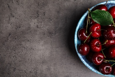 Bowl with delicious sweet cherries on grey table, top view. Space for text