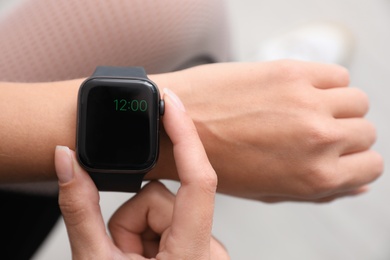 Woman using smart watch to check time indoors, top view