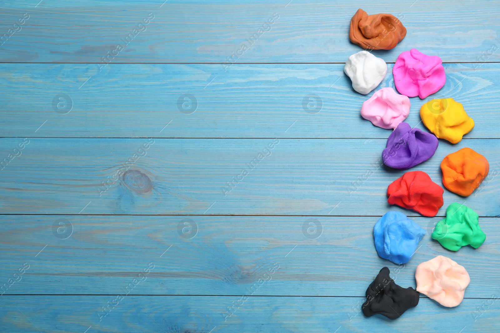 Photo of Many different colorful plasticine on light blue wooden table, flat lay. Space for text