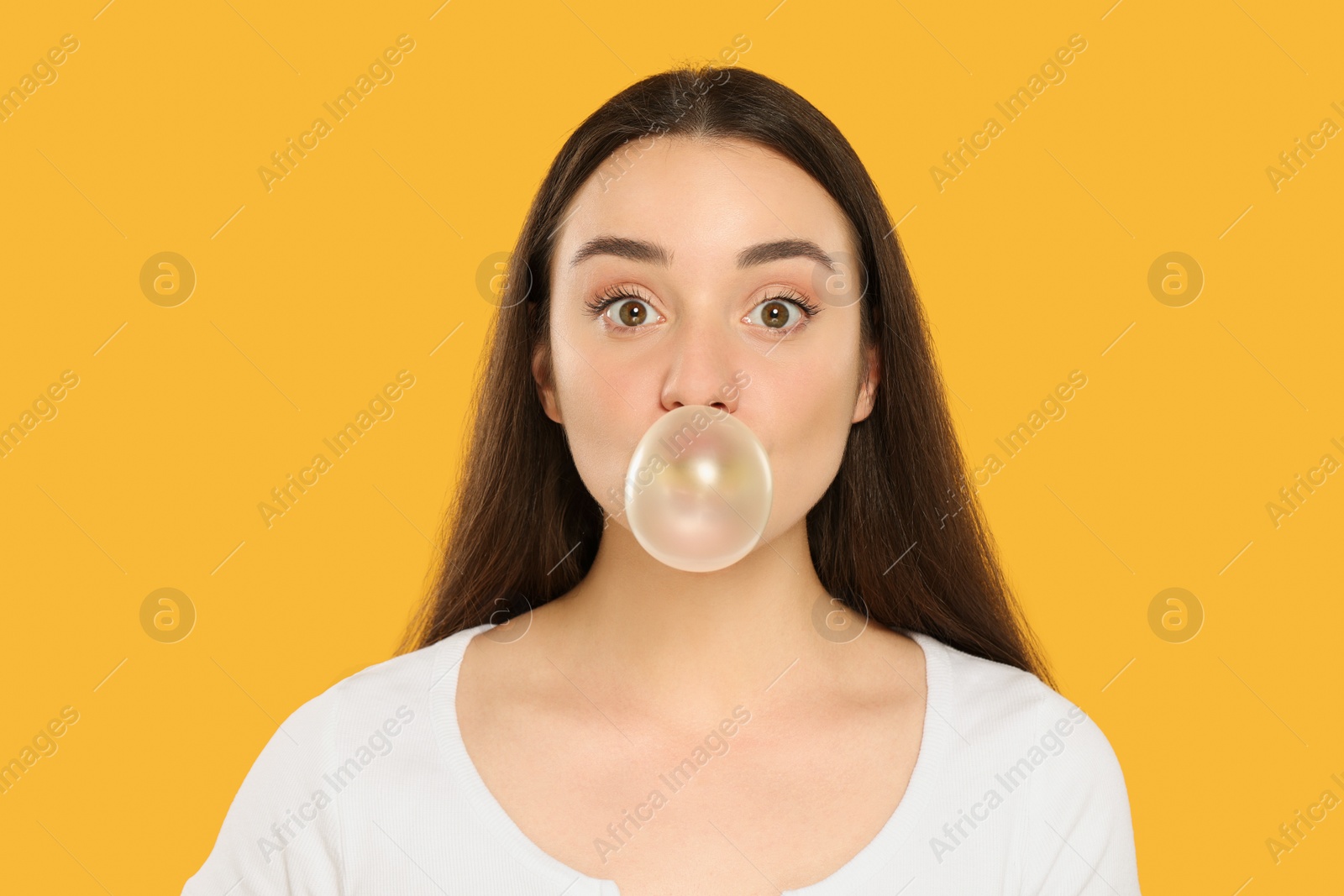 Photo of Beautiful young woman blowing bubble gum on yellow background