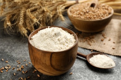 Wooden bowl with wheat flour on grey table