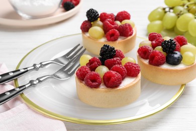 Photo of Delicious tartlets with berries on white wooden table