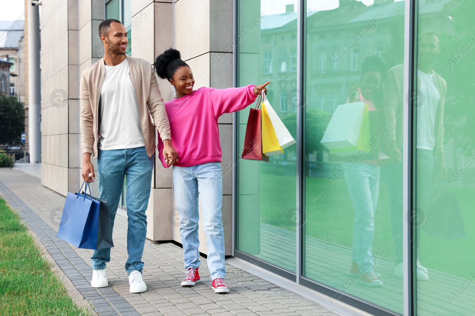 Photo of Family shopping. Happy couple with colorful bags near mall outdoors