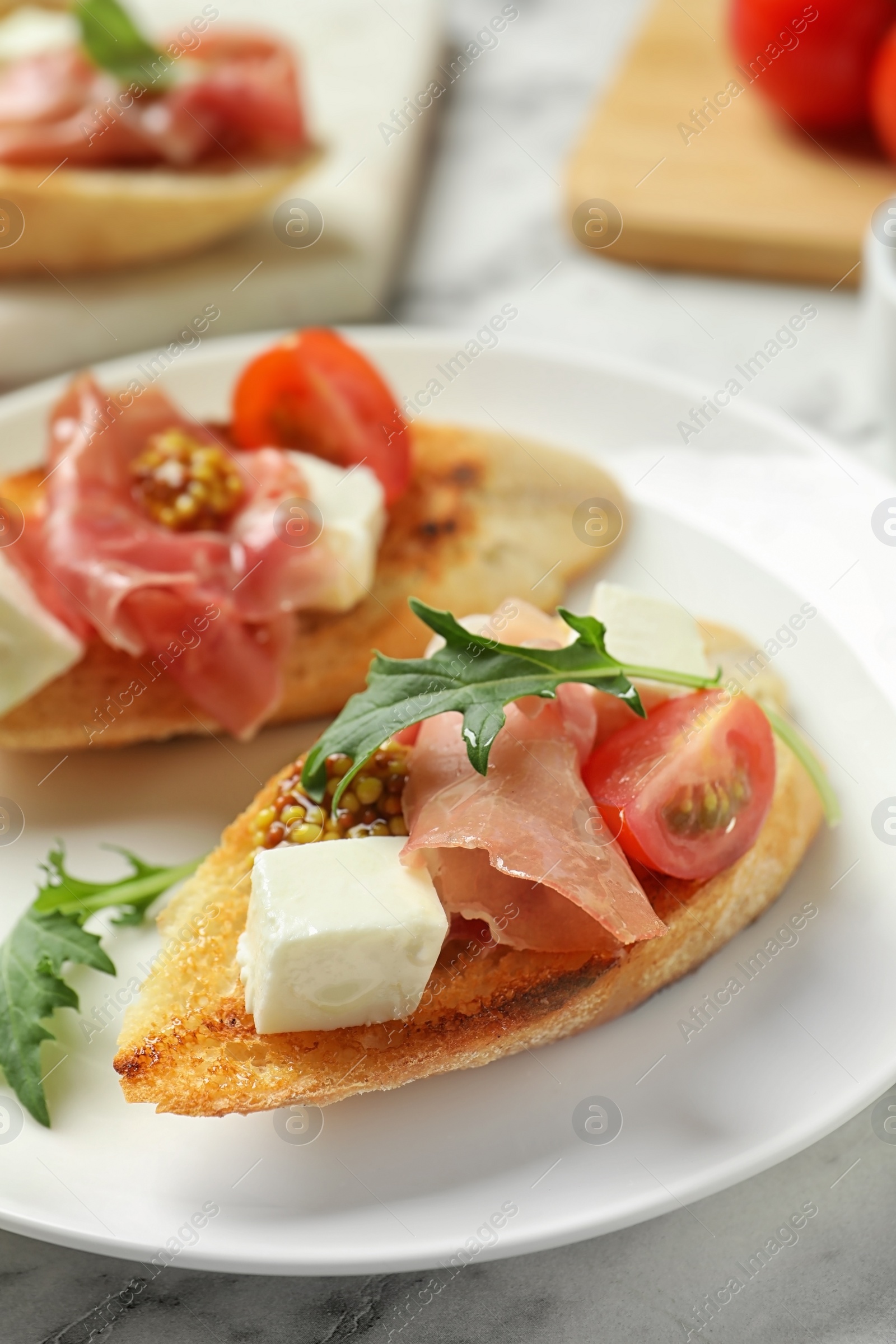 Photo of Plate of tasty bruschettas with prosciutto on table