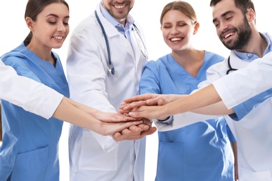Team of medical doctors putting hands together on white background. Unity concept