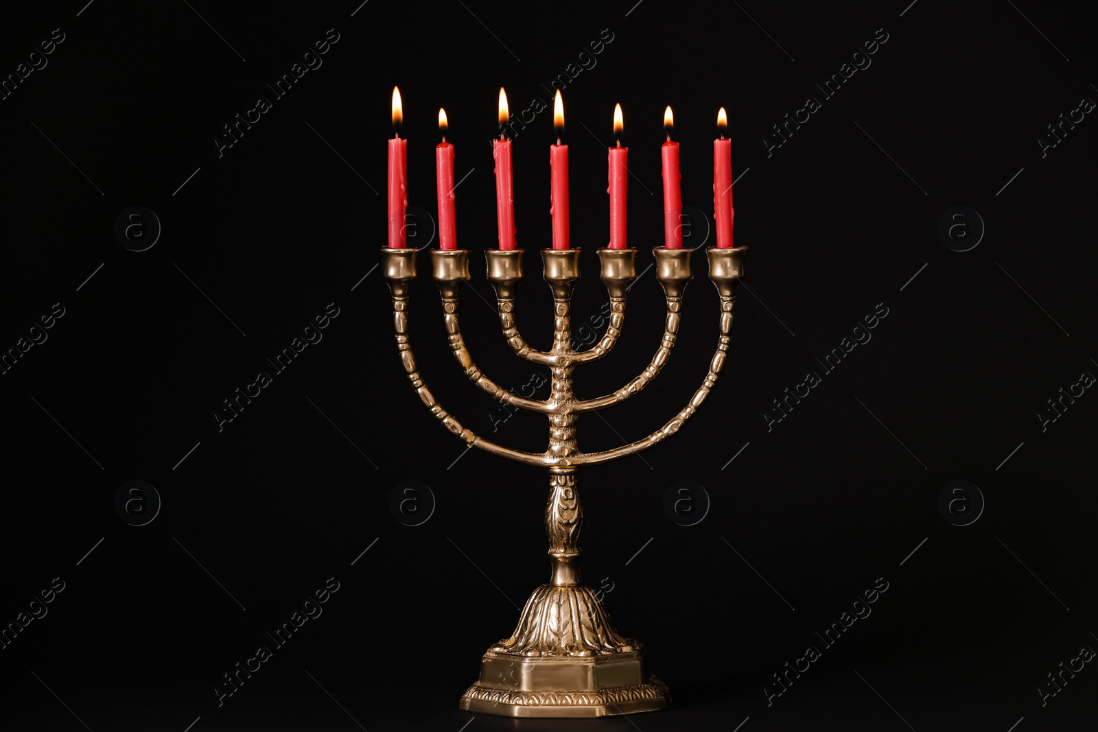 Photo of Golden menorah with burning candles on black background