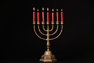 Photo of Golden menorah with burning candles on black background