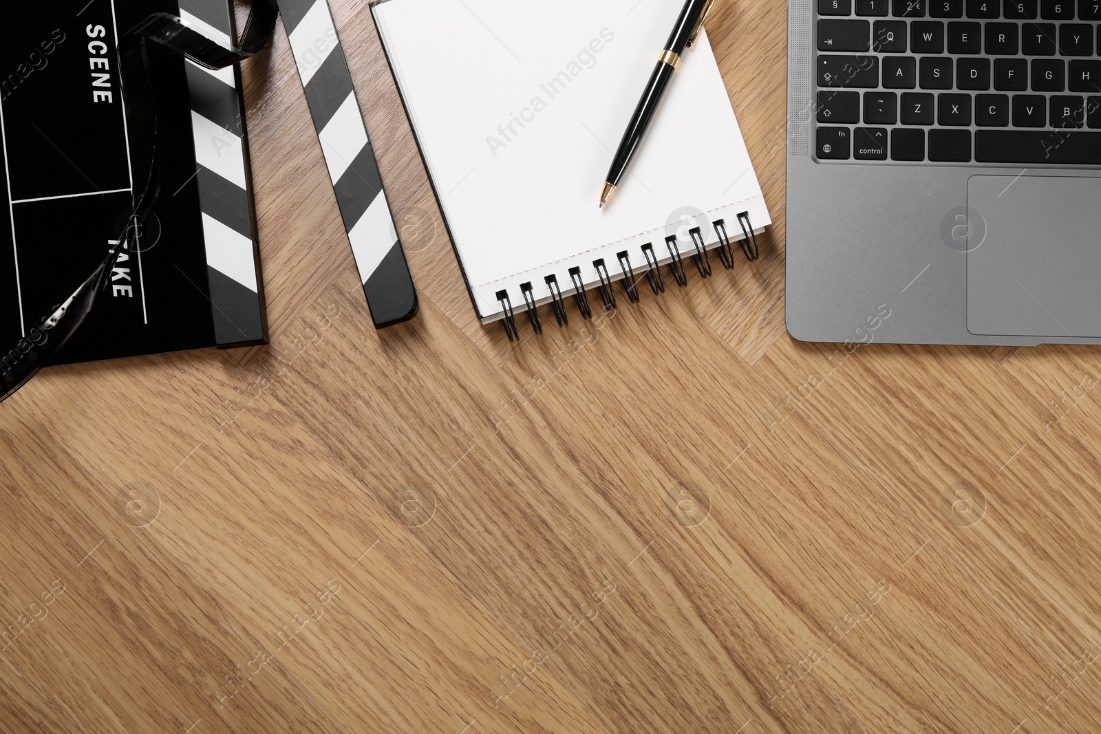 Photo of Movie clapper, film reel, notebook and laptop on wooden table, flat lay. Space for text