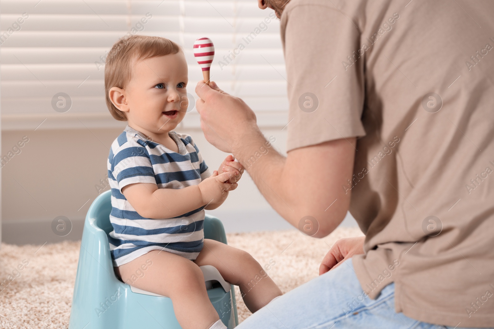 Photo of Father training his child to sit on baby potty indoors