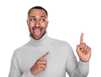 Photo of Happy young man showing his tongue and pointing at something on white background