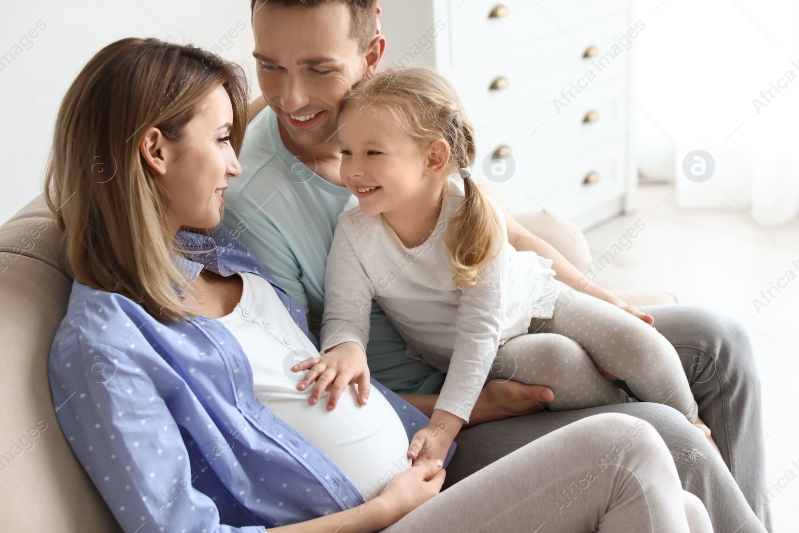 Photo of Young pregnant woman with her family at home