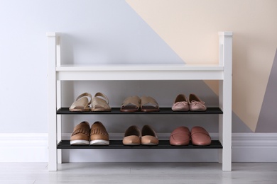 Shoe rack with different footwear near color wall, space for text. Stylish hallway interior