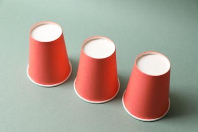 Photo of Three red cups on pale olive background. Thimblerig game