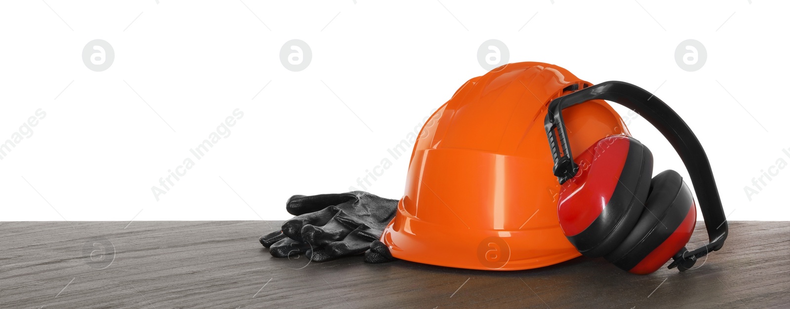 Photo of Hard hat, earmuffs and gloves on wooden table against white background. Safety equipment