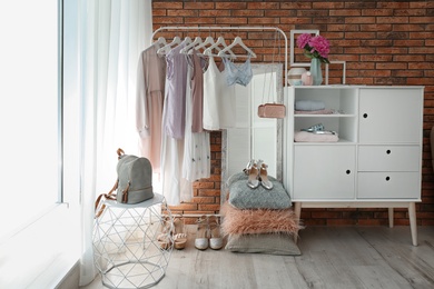 Photo of Stylish dressing room interior with clothes on rack