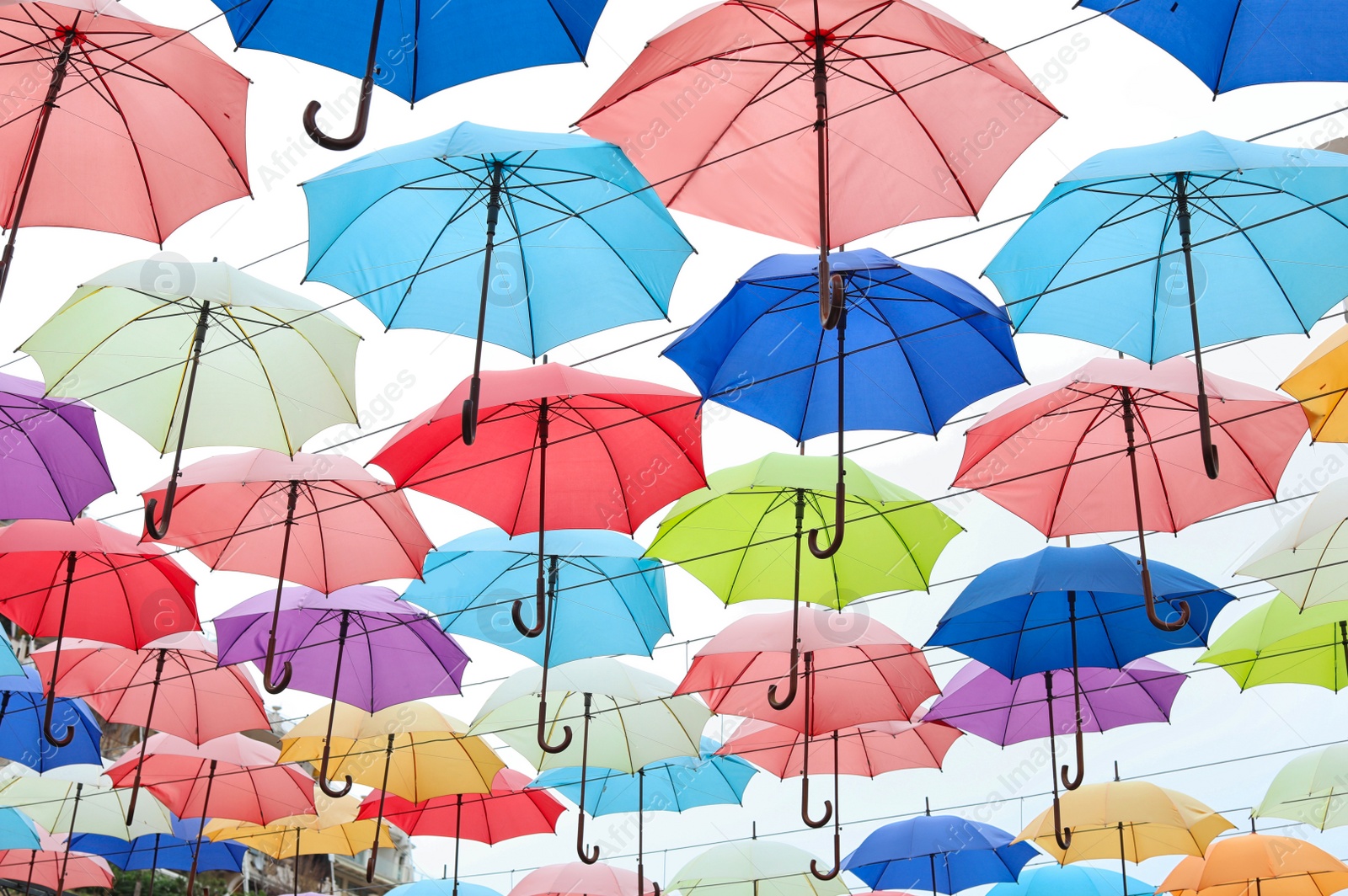 Photo of Many opened multicolored umbrellas on light background