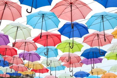 Many opened multicolored umbrellas on light background