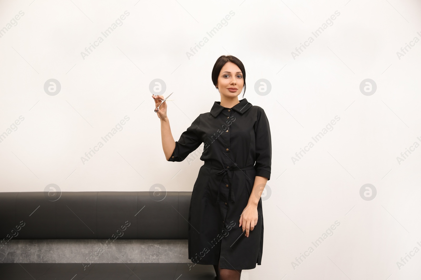 Photo of Professional female hairdresser with comb and scissors in salon