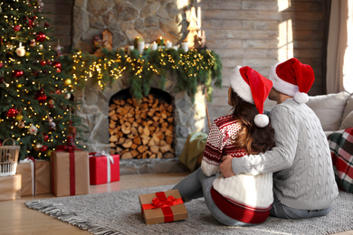 Happy young couple wearing Santa hats in living room decorated for Christmas