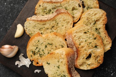 Tasty baguette with garlic and dill on grey textured table, top view