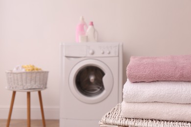 Photo of Clean folded towels on wicker basket in laundry room. Space for text