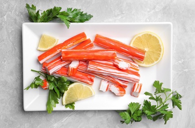 Photo of Delicious crab sticks served on light grey marble table, flat lay