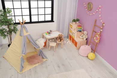 Photo of Modern nursery room interior with play tent for kids