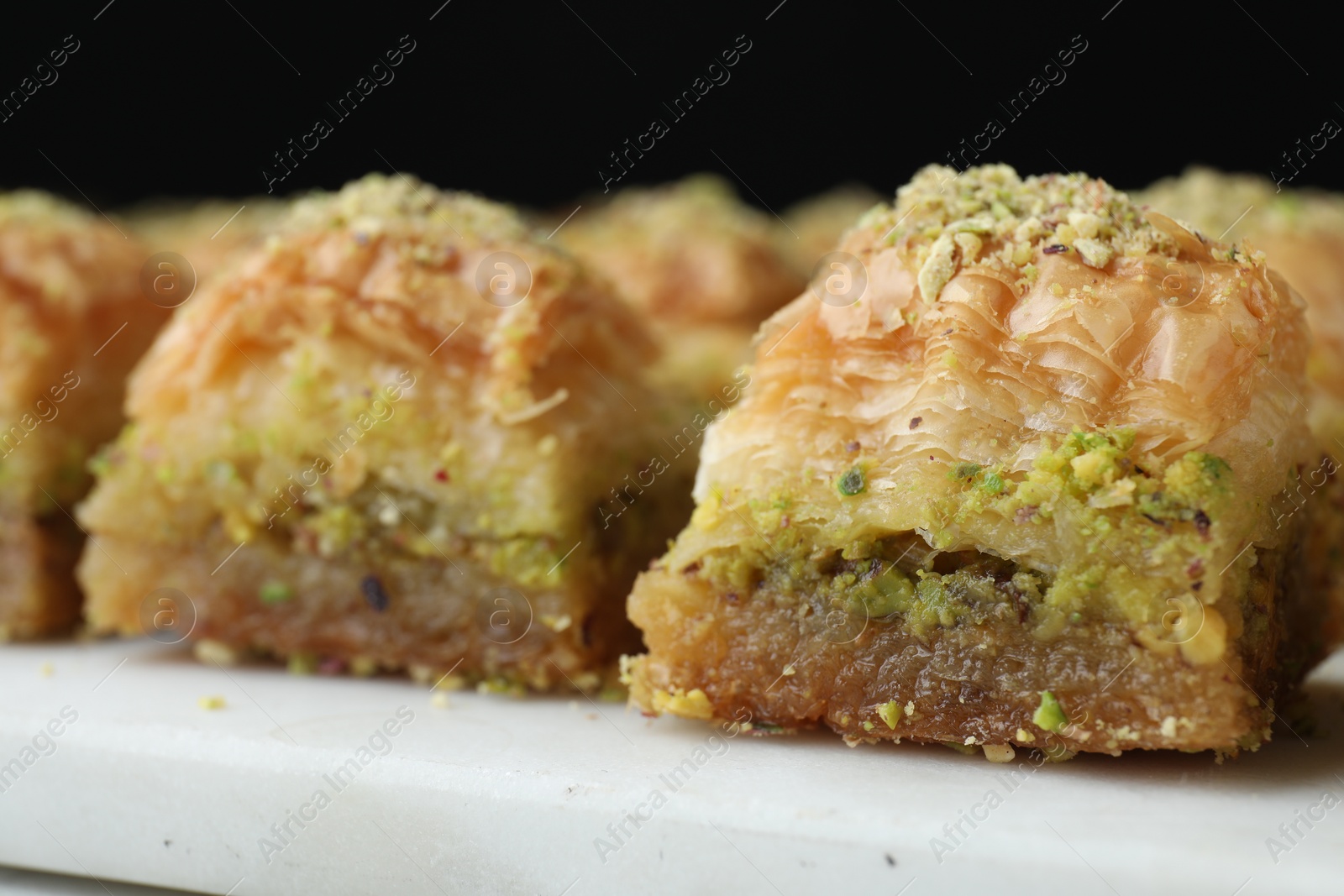 Photo of Delicious fresh baklava with chopped nuts on white table, closeup. Eastern sweets