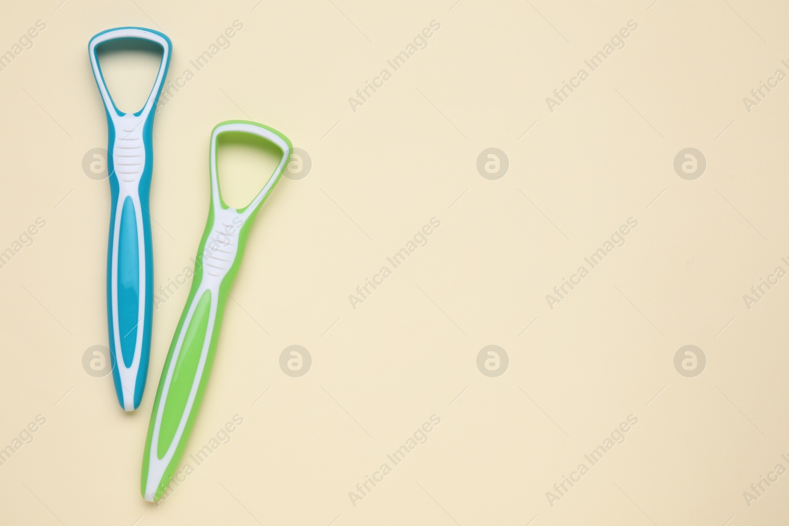 Photo of Colorful tongue cleaners on beige background, flat lay. Space for text