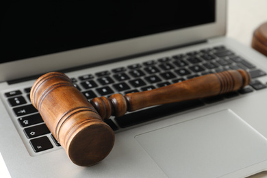 Photo of Modern laptop and wooden gavel on table, closeup. Cyber crime