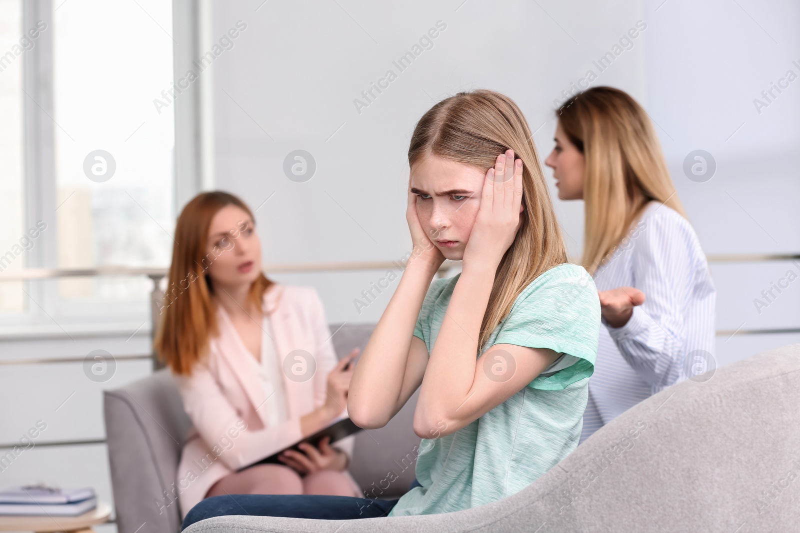 Photo of Young female psychologist working with teenage girl and her mother in office