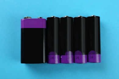Different batteries on turquoise background, flat lay