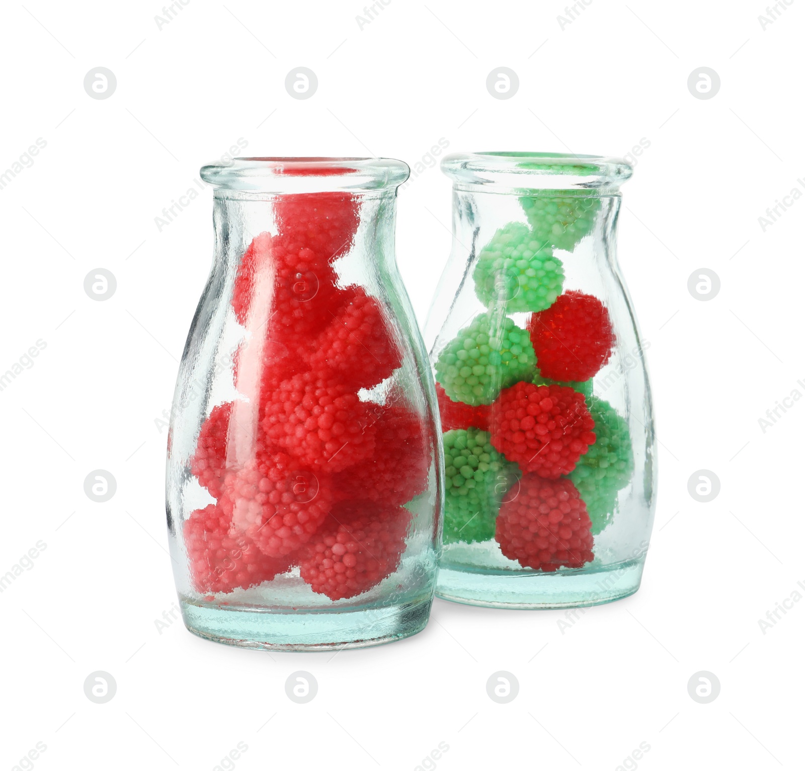 Photo of Delicious gummy raspberry candies in glass bottles on white background