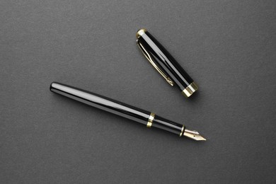 Stylish fountain pen with cap on dark background, flat lay