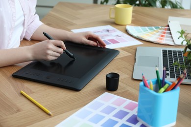 Professional designer with graphic tablet at wooden table, closeup