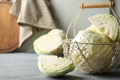 Photo of Basket with fresh cabbages on grey wooden table
