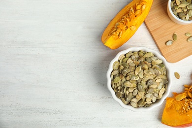 Photo of Flat lay composition with raw pumpkin seeds on white wooden table, space for text