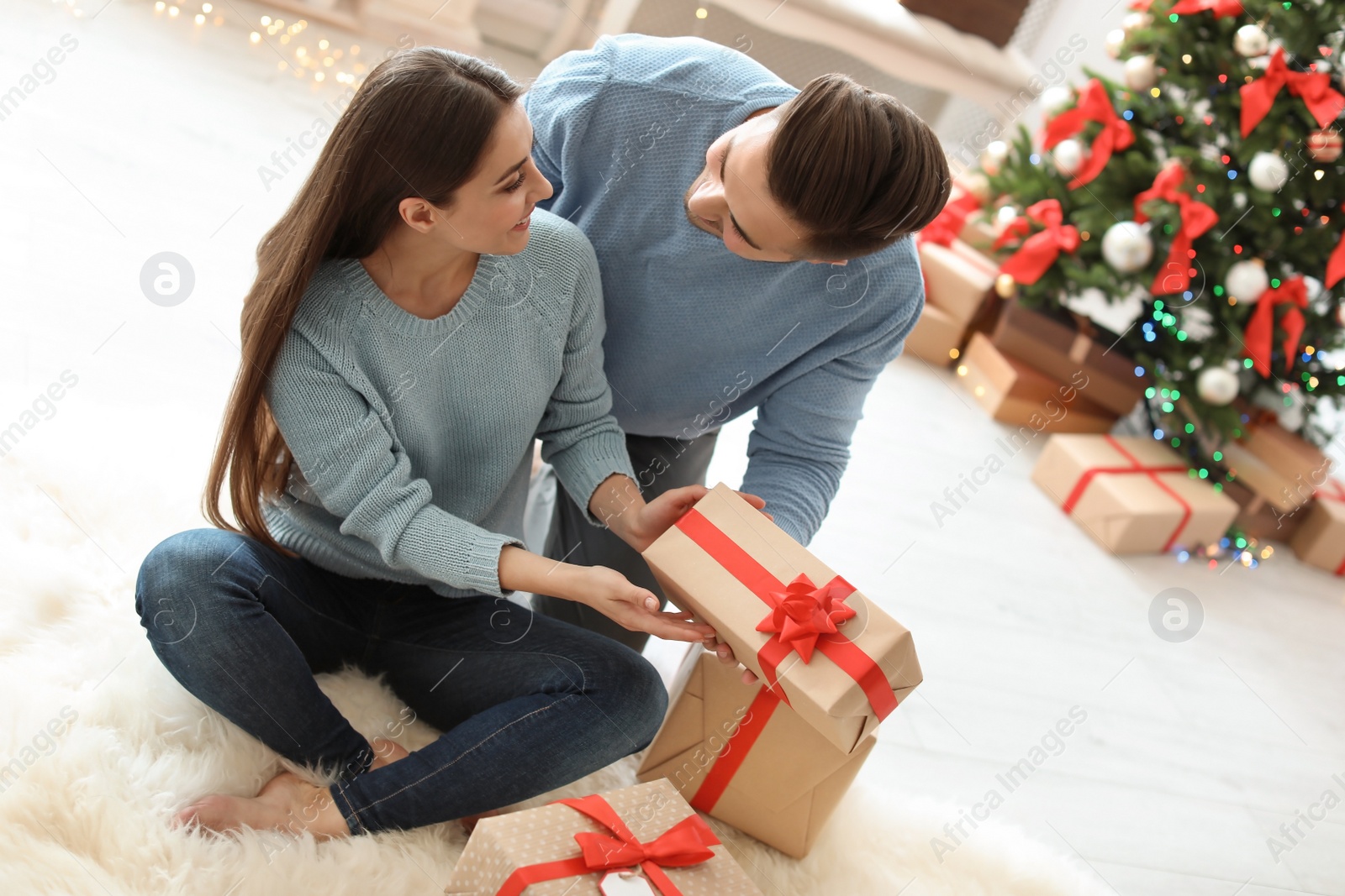 Photo of Young man giving Christmas gift to his girlfriend at home