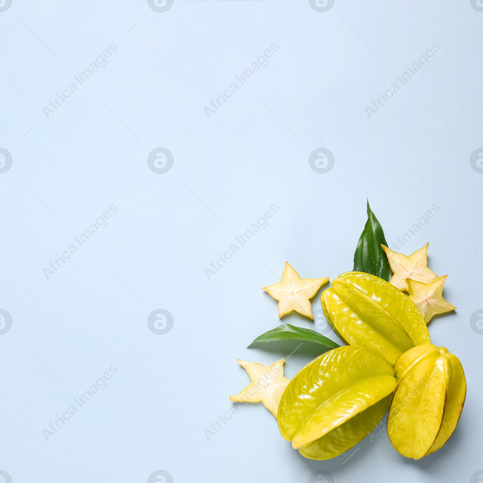 Photo of Delicious carambola fruits on light blue background, flat lay. Space for text