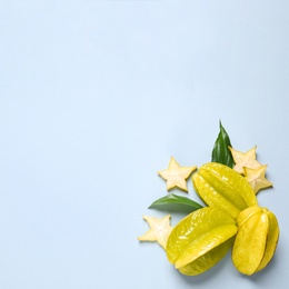 Delicious carambola fruits on light blue background, flat lay. Space for text