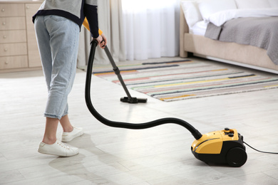 Young woman using vacuum cleaner at home, closeup