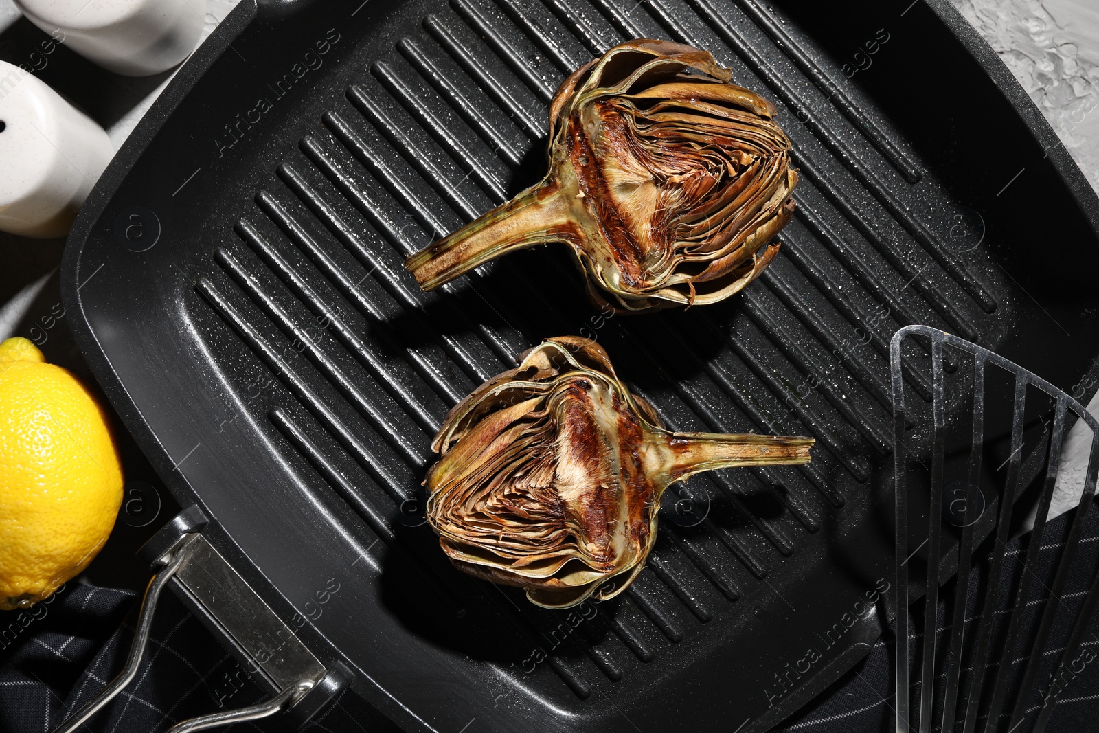 Photo of Pan with tasty grilled artichokes on table, flat lay