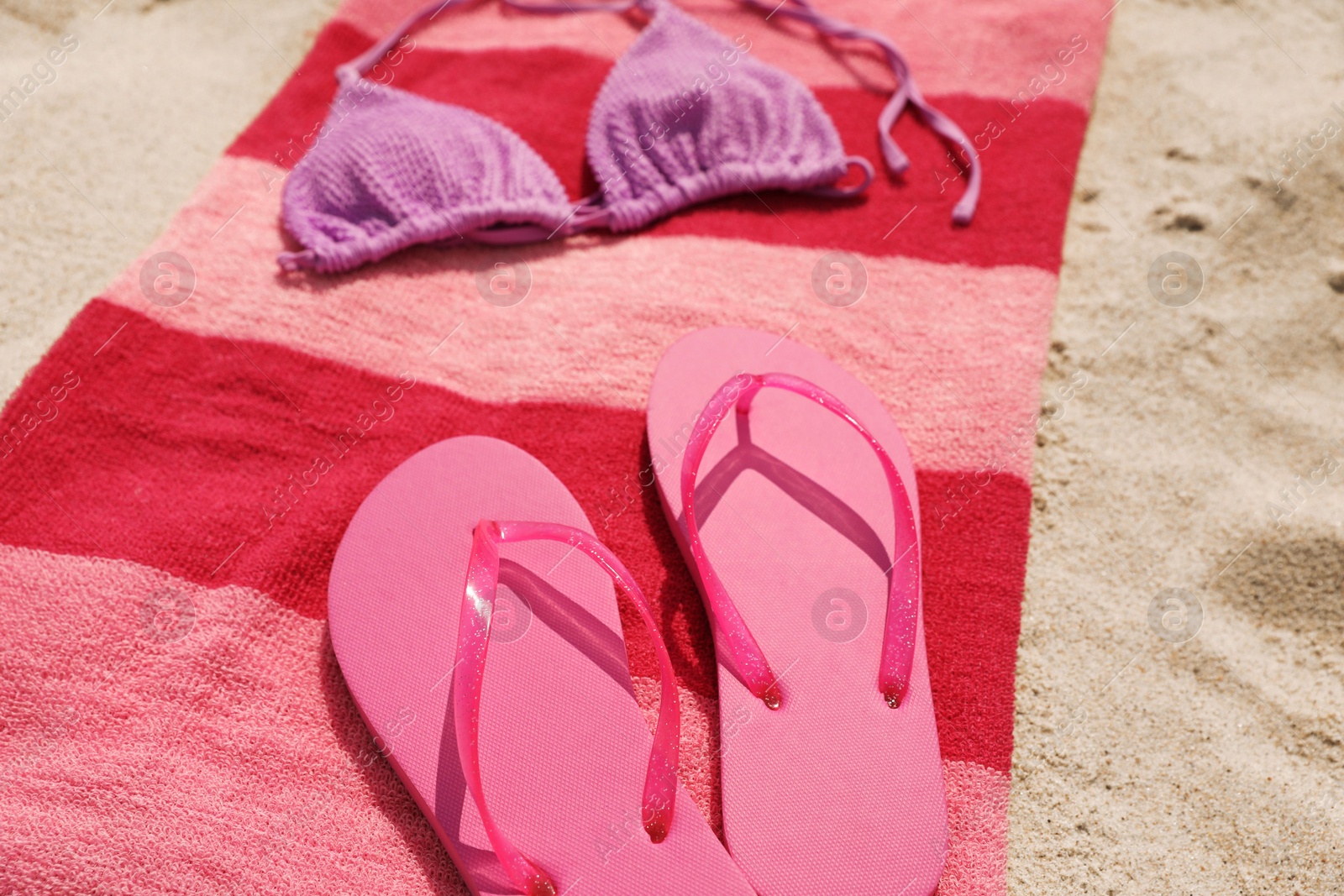 Photo of Beach towel with slippers and swimsuit on sand