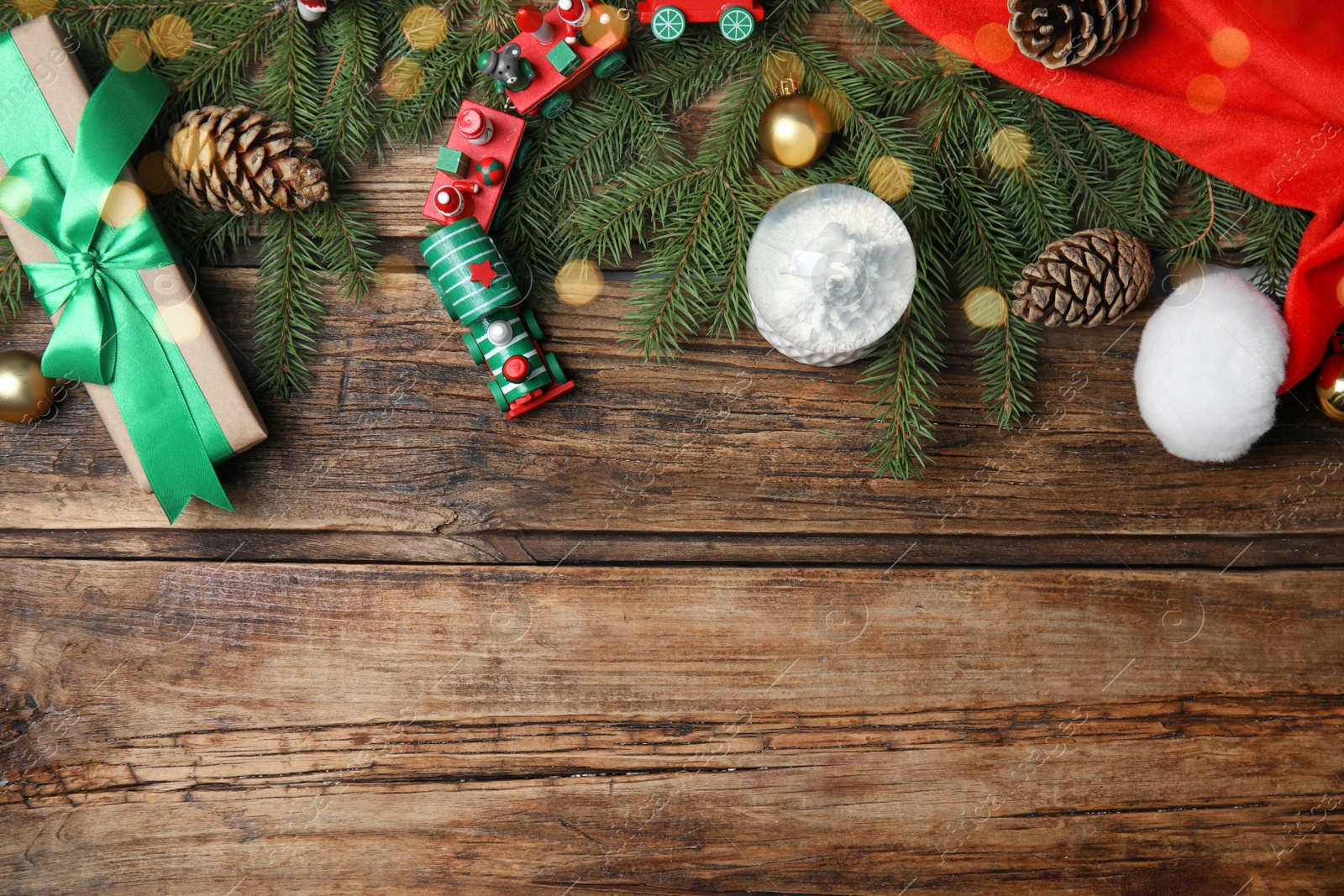 Photo of Christmas greeting card with space for text. Flat lay composition of fir tree branches and festive decor on wooden background