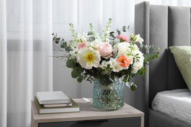 Photo of Bouquet of beautiful flowers on bedside table indoors