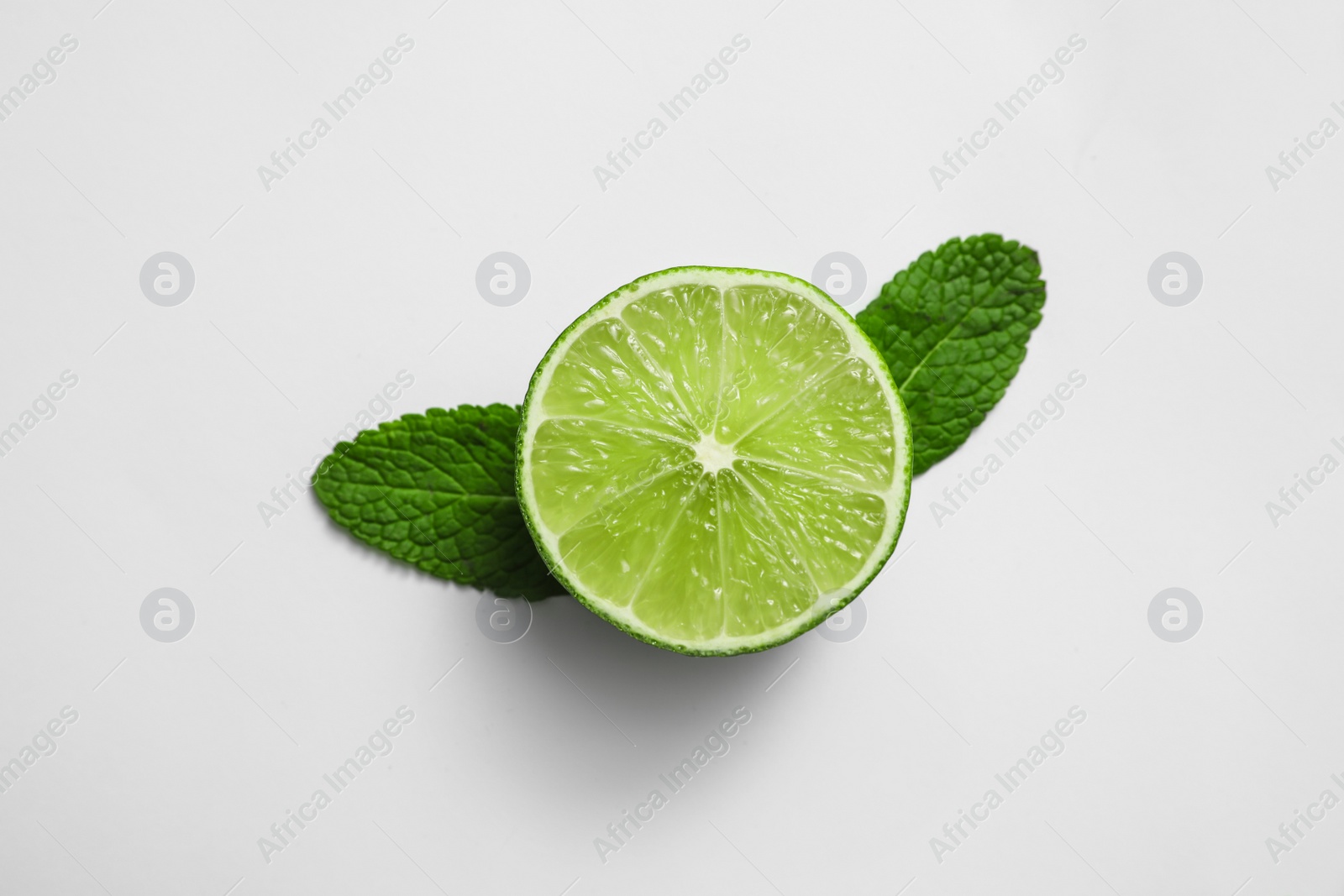 Photo of Cut fresh juicy lime and mint on white background, top view